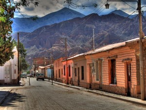 Calle de Tilcara, en Jujuy, casas de frente rosado de una sola planta, detrás las montañas