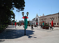 Calle peatonal en la ciudad de Lules; faroles adornados, suelo de concreto, al fondo, edificios públicos