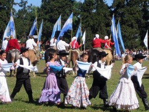 Grupo de niños baila danza típica argentina llevando banderas del país
